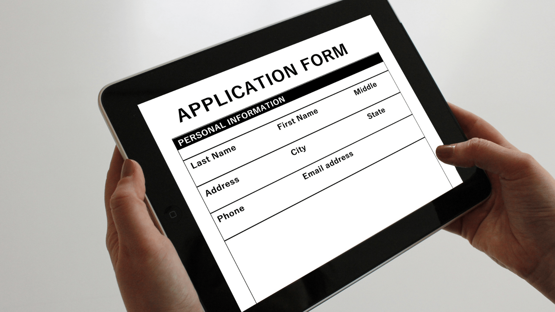 Person holding iPad displaying a generic application form