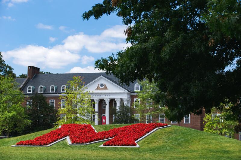 View of The M with red flowers in bloom and Symons hall in the background.